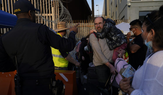 Ukrainian refugees speak with a U.S. Customs and Border Protection official as the refugees prepare to cross the border on April 4, 2022, in Tijuana, Mexico.