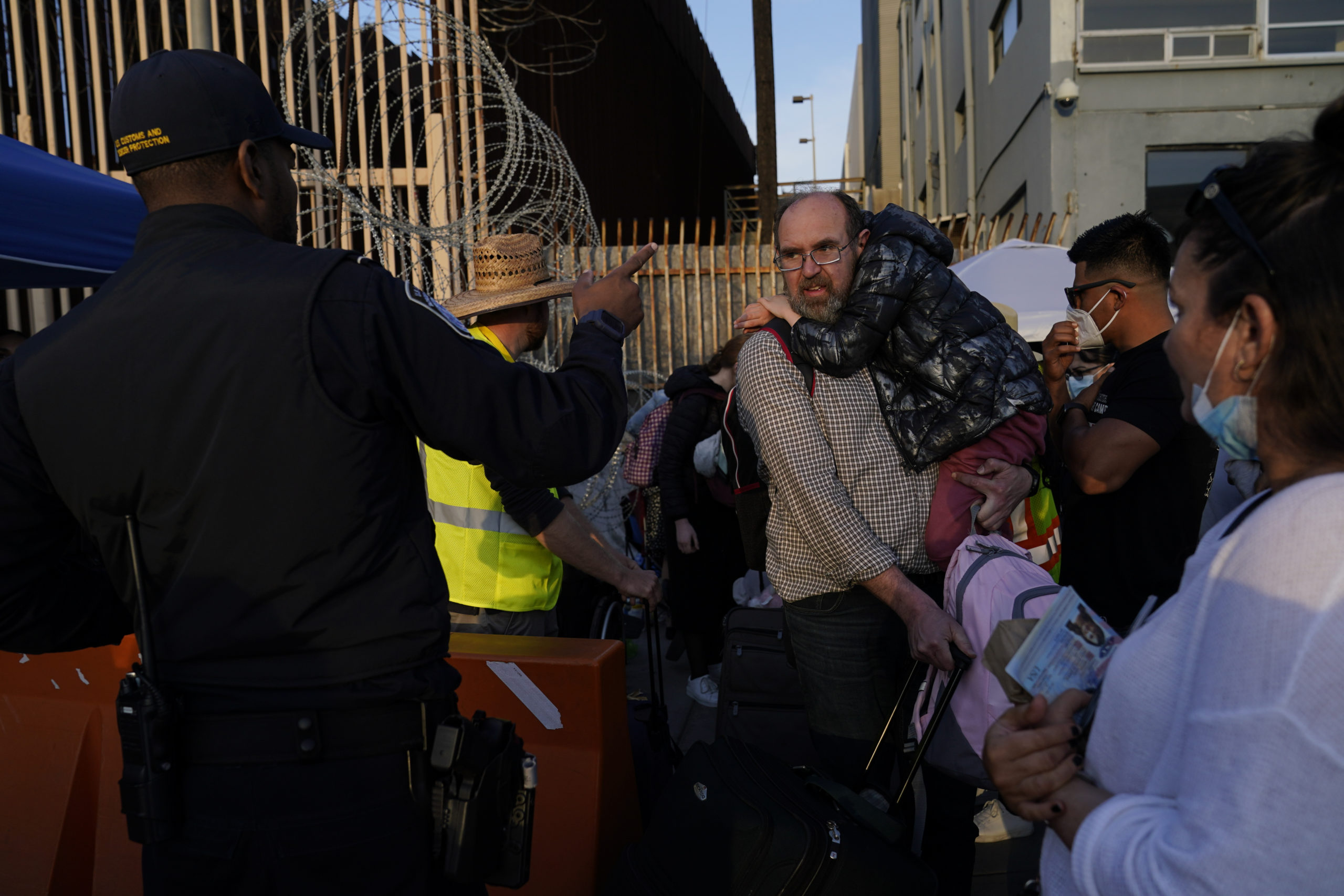 Ukrainian refugees speak with a U.S. Customs and Border Protection official as the refugees prepare to cross the border on April 4, 2022, in Tijuana, Mexico.