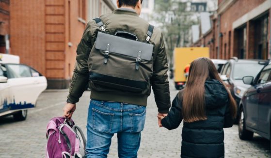 This stock image shows a father walking his daughter to school.