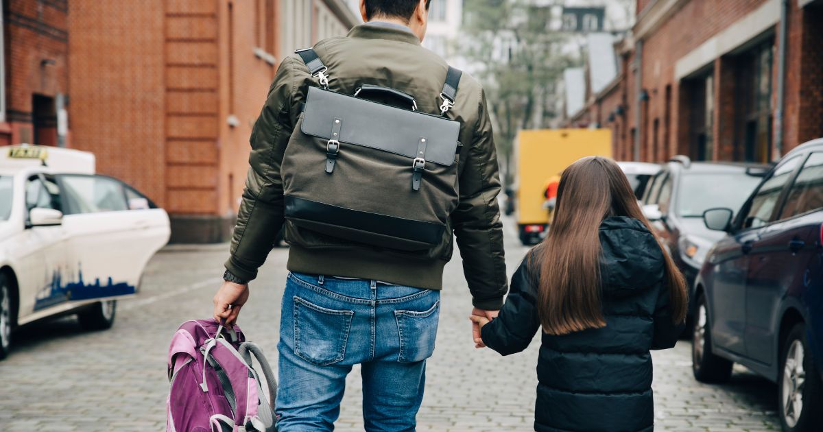 This stock image shows a father walking his daughter to school.