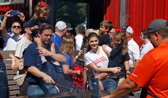 With daughter Mamie, 3, on his shoulders, Florida Governor and Republican presidential candidate Ron DeSantis and his wife Casey DeSantis holding their daughter Madison, 6, work the grill at the Iowa Pork Producers Tent at the Iowa State Fair on Aug. 12 in Des Moines, Iowa.