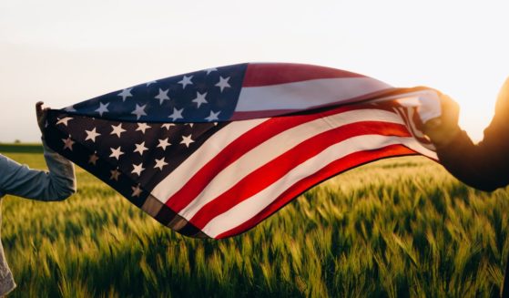 People hold an American flag in the above stock image.