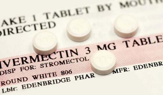 Four ivermectin pills are displayed on top of usage instructions for the drug.