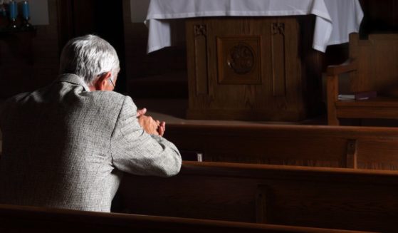 A man prays in a church in this stock image.