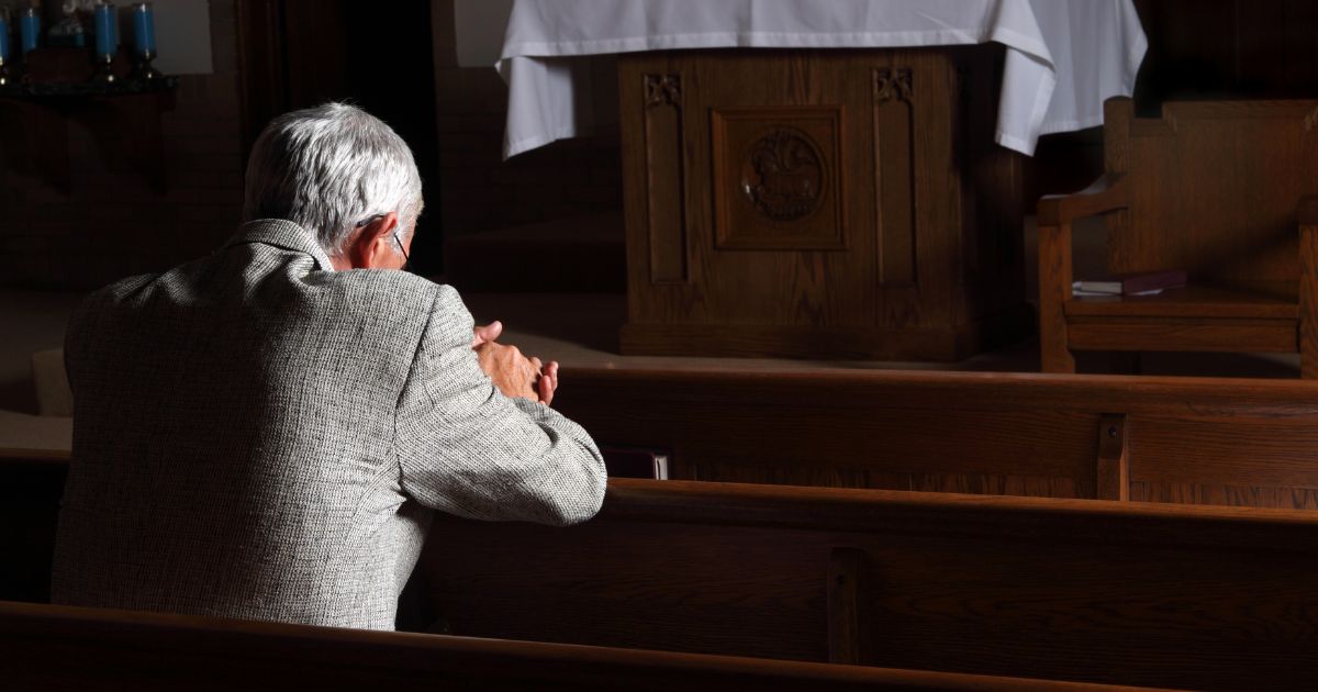 A man prays in a church in this stock image.