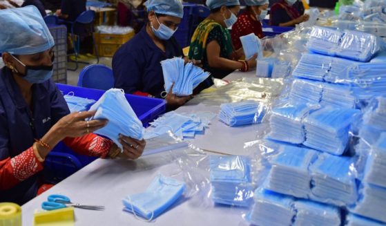 Employees wearing facemasks as a preventive measure against the Covid-19 coronavirus, work at the production and packing of the facemasks at Salus Products, a manufacturer of surgical disposable products, on the outskirts of Ahmedabad on December 28, 2022.