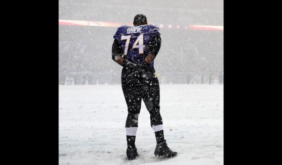 Tackle Michael Oher #74 of the Baltimore Ravens stands on the snow covered field during the national anthem before playing the Minnesota Vikings at M&T Bank Stadium on December 8, 2013 in Baltimore, Maryland. The Baltimore Ravens won, 29-26.