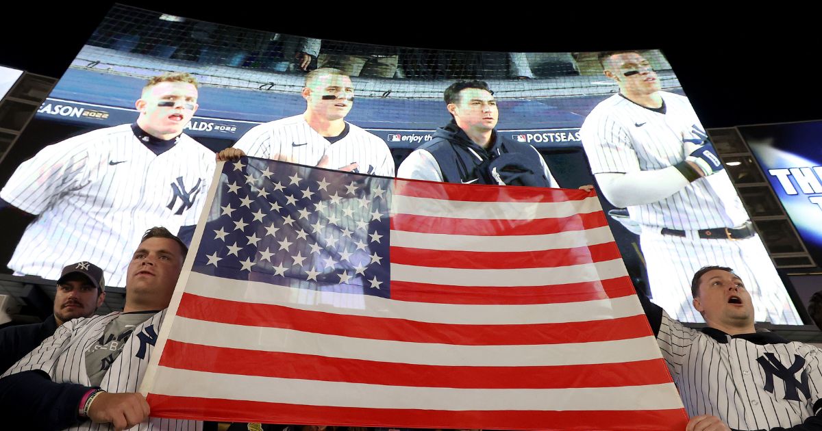 Fans display an American flag during the singing of 'God Bless America' in game five of the American League Division Series between the Cleveland Guardians and New York Yankees at Yankee Stadium on October 18, 2022 in New York, New York.