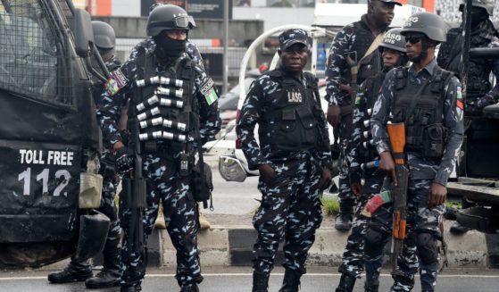 Police officers stand as supporters march to campaign for candidate of Labour Party Peter Obi during a campaign rally in Lagos, on Oct. 1, 2022.