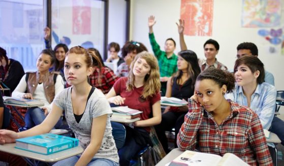 This stock image shows teenage students in a classroom setting.