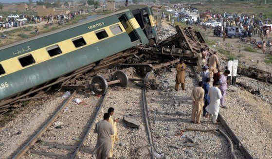 Local residents examine damaged cars of a passenger train which was derailed near Nawabshah, Pakistan, on Sunday.