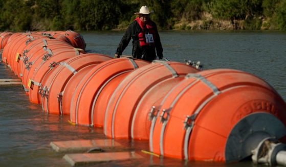 A kayaker walks past large buoys being used as a floating border barrier on the Rio Grande in Eagle Pass, Texas, on Aug. 1.