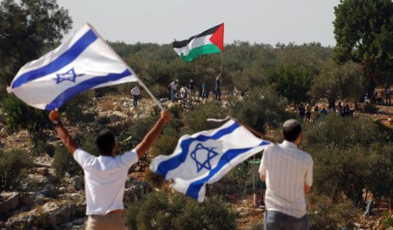 Israeli activists hold Israeli flags as a Palestinian activist waves a Palestinian flag at the barrier between the West Bank village of Nilin and the Jewish settlement of Hashmonaim on Oct. 17, 2008.