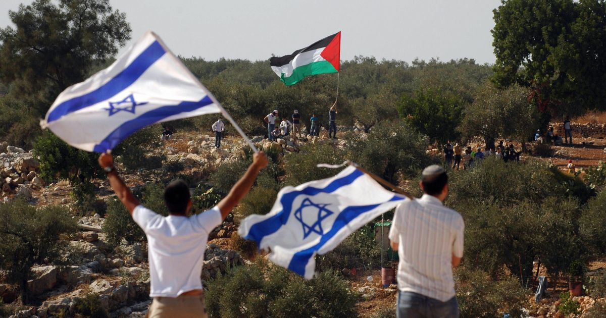 Israeli activists hold Israeli flags as a Palestinian activist waves a Palestinian flag at the barrier between the West Bank village of Nilin and the Jewish settlement of Hashmonaim on Oct. 17, 2008.