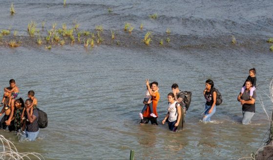 Migrants walk in the Rio Grande in Mexico, across from Eagle Pass, Texas, in a July photo.