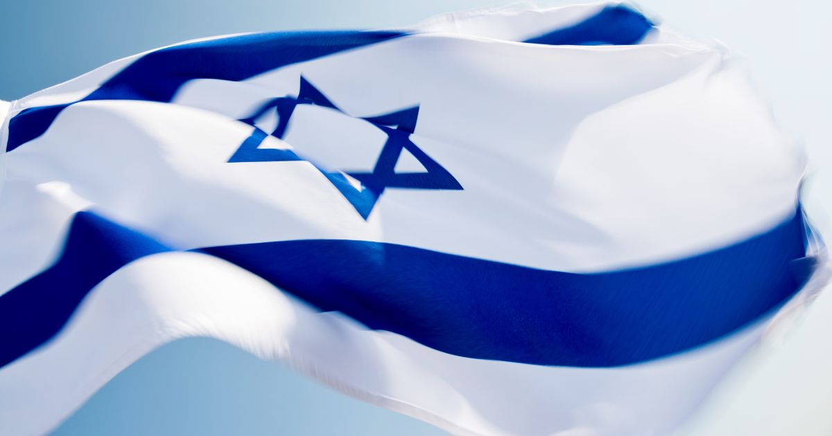 The Israeli flag flies in the above stock image.
