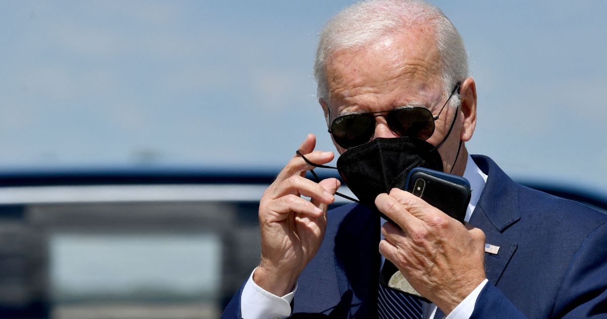 President Joe Biden removes a mask after leaving Air Force One at Joint Base Andrews in Maryland on Aug. 16, 2022.