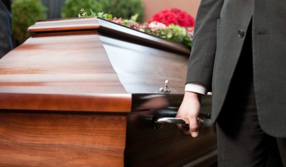 A pallbearer lifts a casket in this stock image.