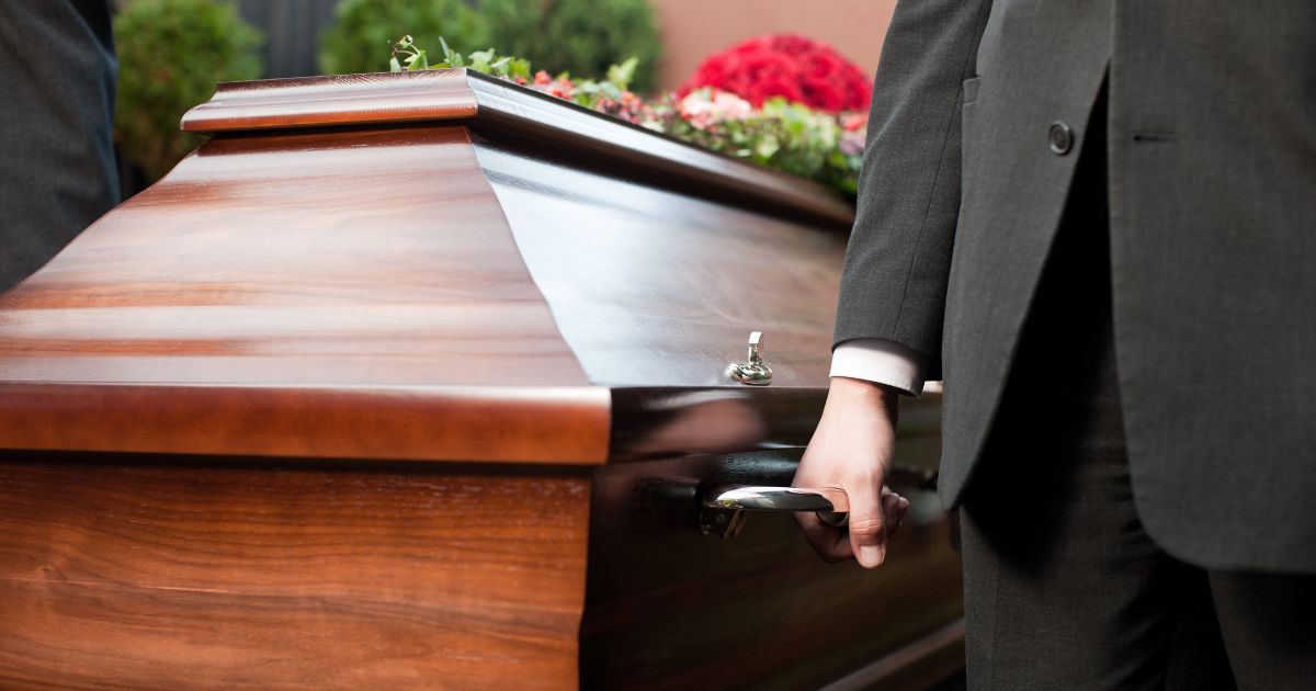A pallbearer lifts a casket in this stock image.