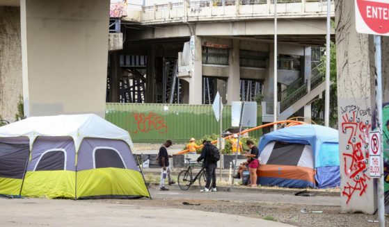 People are seen in a homeless encampment under the Morrison Bridge in downtown Portland, Oregon, on Aug. 8.