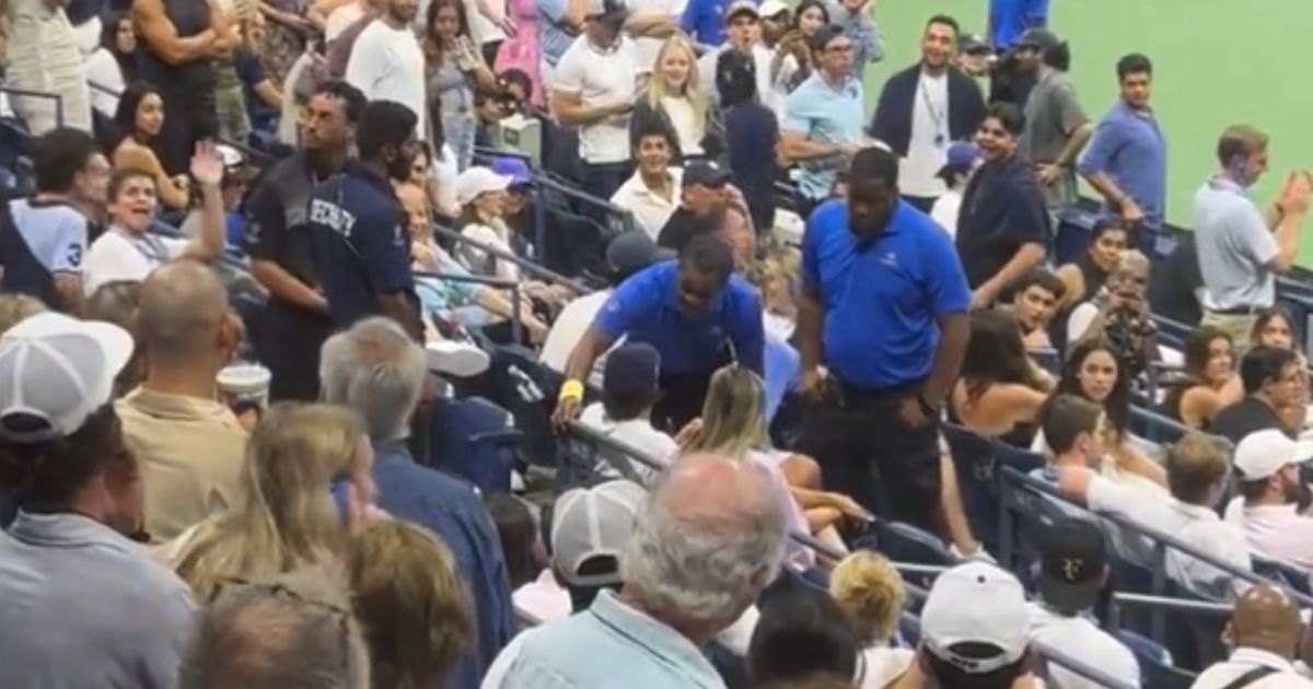 Security guards talk to a fan at the U.S. Open before ejecting him.