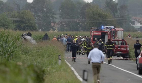 Car debris is seen at left as firefighters seal off the area where an aircraft of an Italian acrobatic air team crashed during a practice run outside of Turin, Italy, on Saturday.