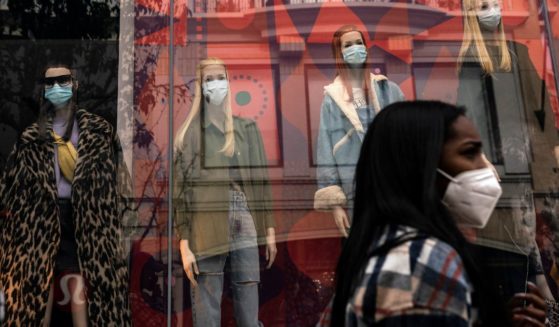 A shopper walks past mannequins donning face masks