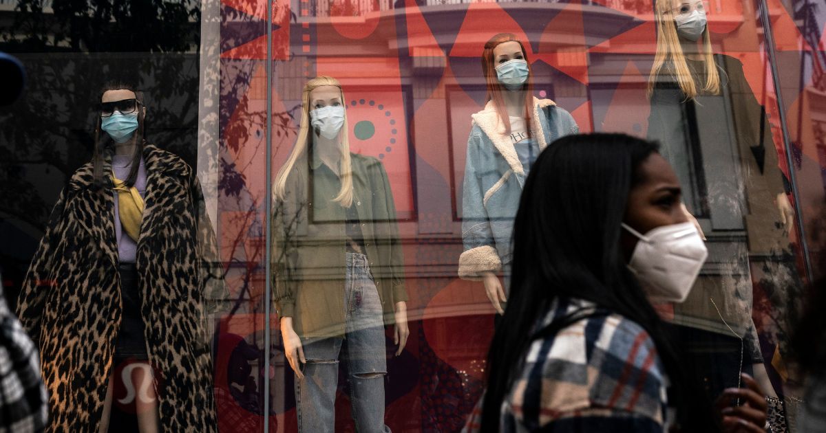 A shopper walks past mannequins donning face masks