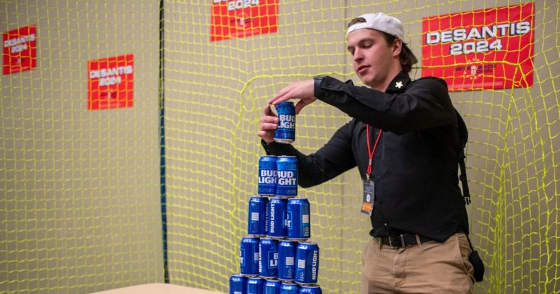 An employee builds a tower of Bud Light beer cans for ball target practice in the Ron DeSantis booth at the Republican Party of Iowa's 2023 Lincoln Dinner at the Iowa Events Center in Des Moines, Iowa, on July 28, 2023.