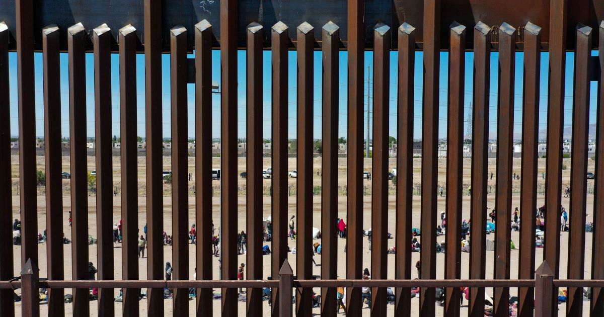 Illegal migrants wait along the border wall to surrender to U.S. Border Patrol agents after crossing the Rio Grande into the U.S. in El Paso, Texas, on May 11.