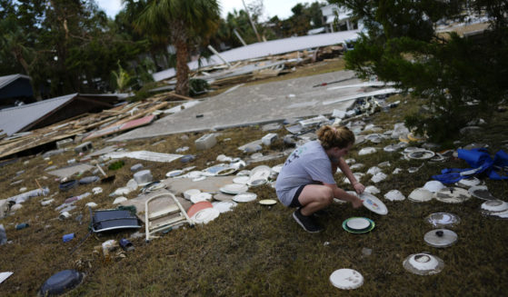Lainey Hamelink, 9, whose family owned the property next door, helps to collect scattered dishes at Tina's Dockside Inn, which was completely destroyed in Hurricane Idalia, on September 1, 2023 in Horseshoe Beach, Florida.