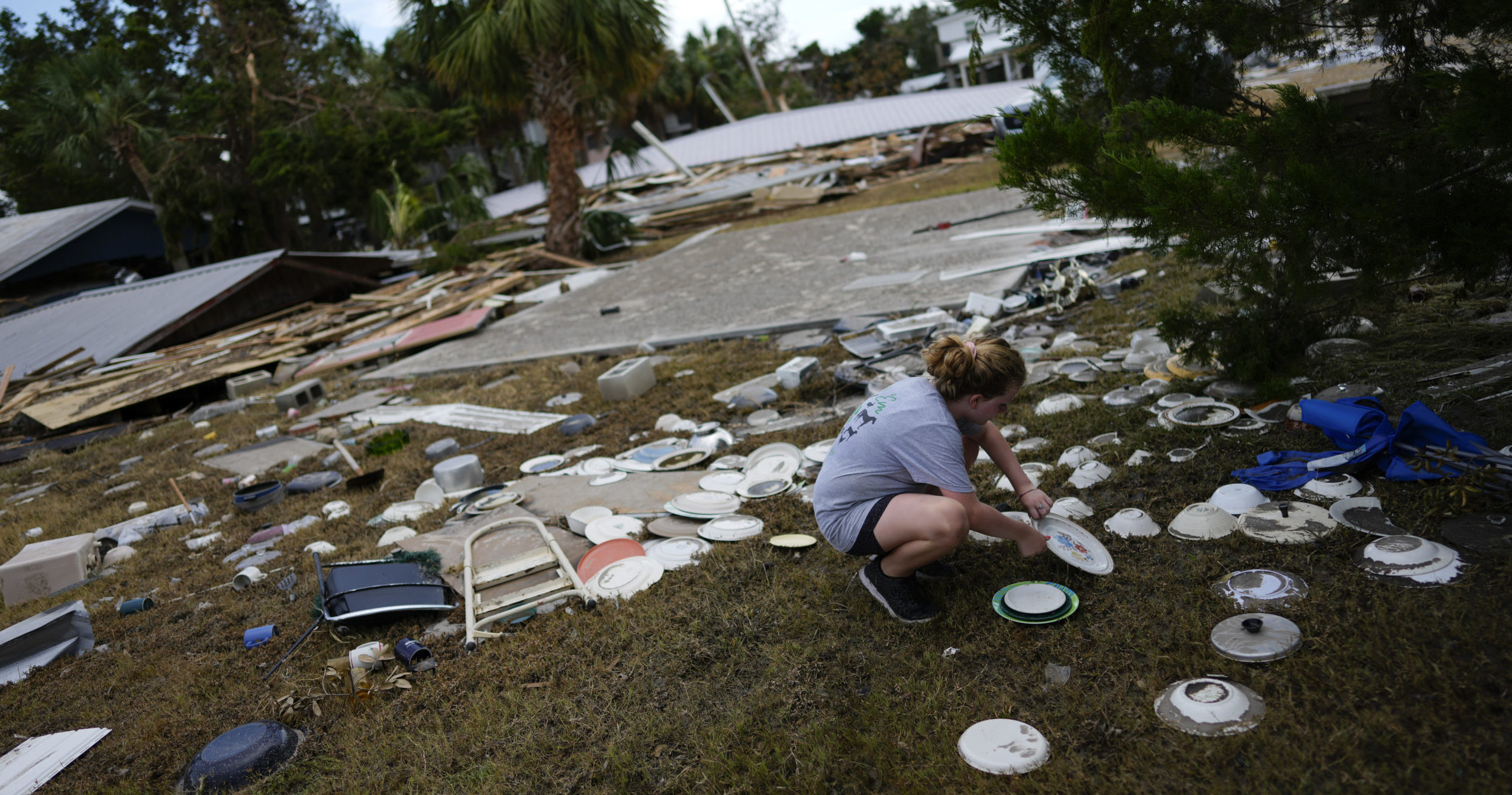 Lainey Hamelink, 9, whose family owned the property next door, helps to collect scattered dishes at Tina's Dockside Inn, which was completely destroyed in Hurricane Idalia, on September 1, 2023 in Horseshoe Beach, Florida.