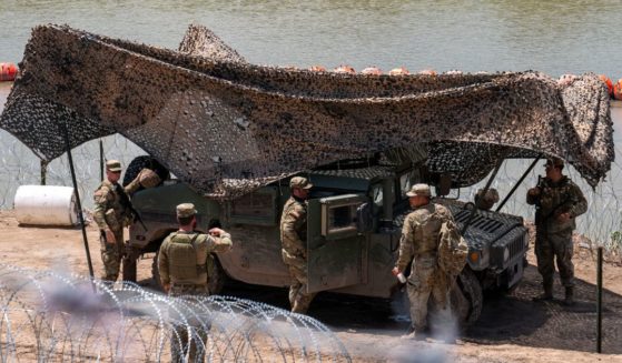 National Guard troops stand guard near a string of buoys placed on the water along the Rio Grande border with Mexico in Eagle Pass, Texas, on Aug. 24.