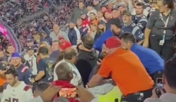 football fans fighting while bystanders try to break them up