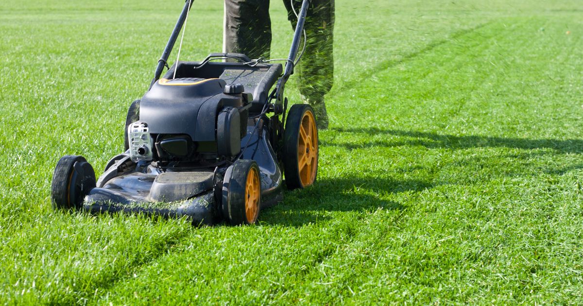 A man uses a lawn mower in the above stock image.
