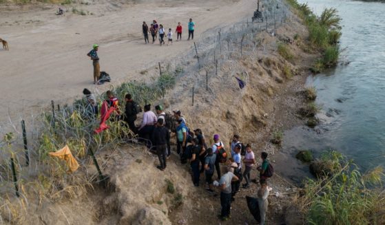 This aerial picture taken on Sunday shows a group of migrants climbing over razor wire as they cross the Rio Grande river at the US-Mexico border to Eagle Pass, Texas.