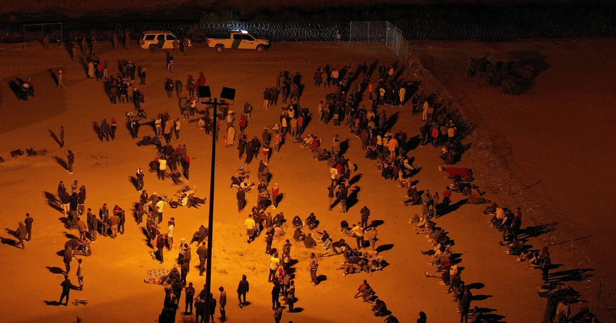 Migrants wait at night along the border wall to surrender to US Customs and Border Protection (CBP) Border Patrol agents for immigration and asylum claim processing before the expiration of Title 42 upon crossing the Rio Grande river from Ciudad Juarez into the United States on the US-Mexico border in El Paso, Texas on May 11, 2023.