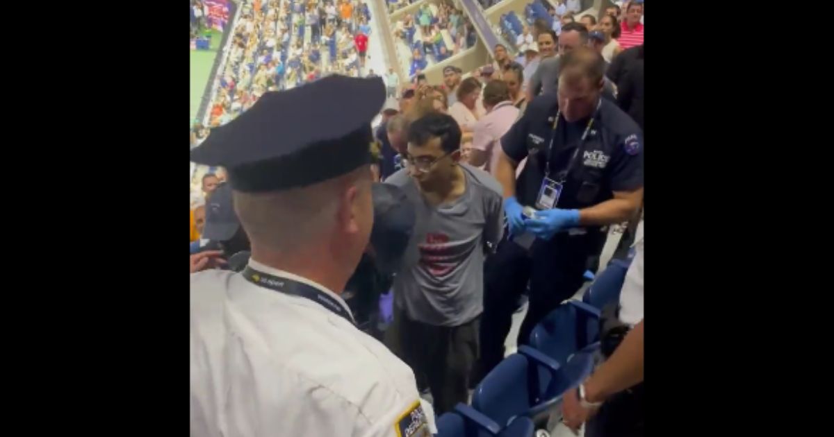 Two men have been charged after they staged a climate protest during a U.S. Open tennis match on Thursday.