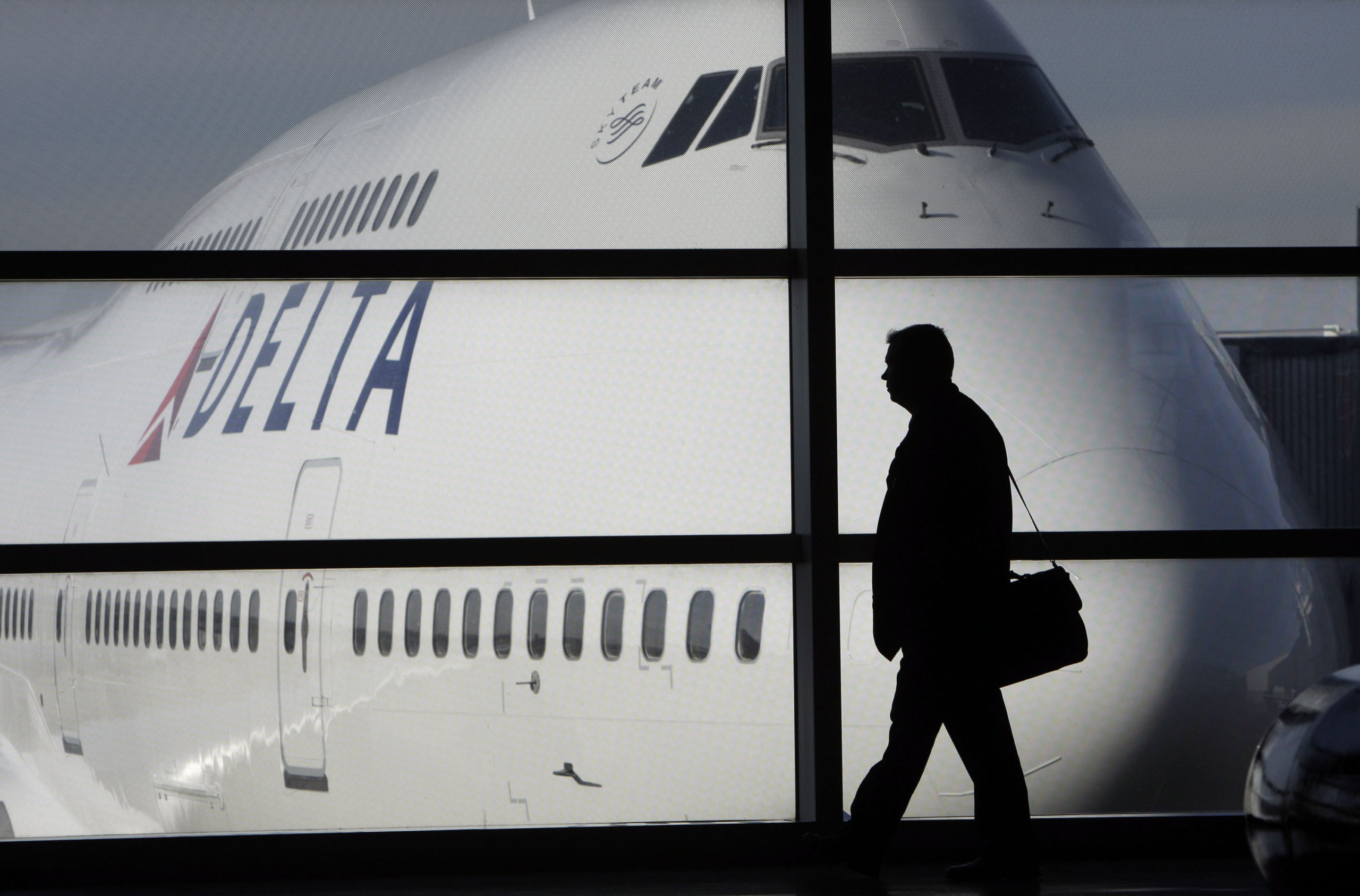 A passenger walks past a Delta Airlines 747 aircraft at Detroit Metropolitan Wayne county Airport in Romulus, Michigan, on Jan. 21, 2010. Several major airlines have announced they are cancelling flights in and out of Israel following the nation's declaration of war on Hamas.