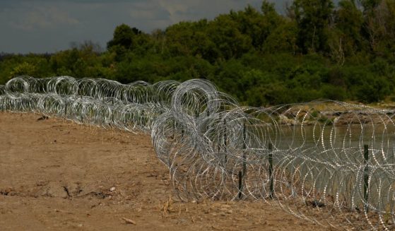 Concertina wire lines the banks of the Rio Grande on the Pecan farm of Hugo and Magali Urbina, near Eagle Pass, Texas, on July 7.