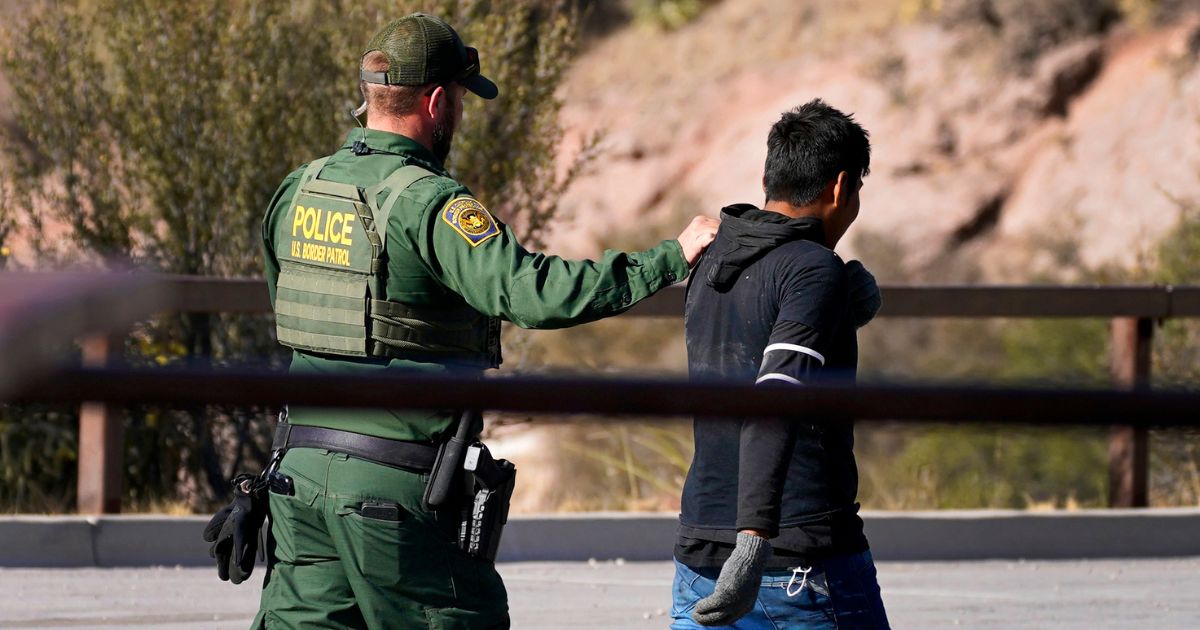 Customs and Border Patrol agent detaining a migrant