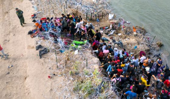 A U.S. Border Patrol agent supervises as immigrants walk into the United States after crossing the Rio Grande from Mexico on September 30 in Eagle Pass, Texas. GOP Sen. John Kennedy of Louisiana said eight million illegal immigrants have flooded the U.S. since President Joe Biden took office in 2021.