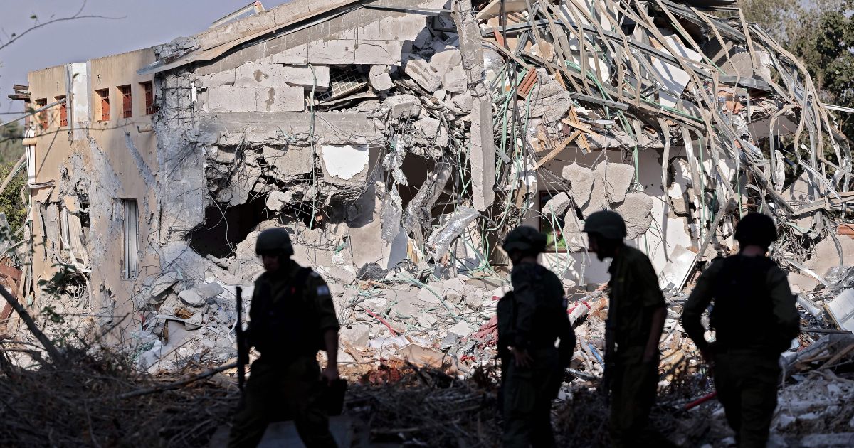 Israeli soldiers walk past a house destroyed by Palestinian Hamas militants in Be'eri near the border with Gaza on Saturday.