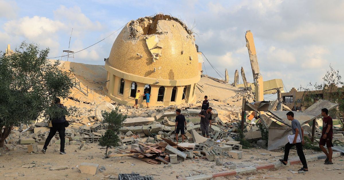 People walk on the ruins of a mosque destroyed in Israeli airstrikes in Khan Yunis, southern Gaza Strip, on Sunday.