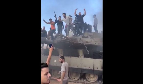 Hamas fighters are seen with a disabled Israeli tank its captured crew on the morning of Oct. 7, 2023.