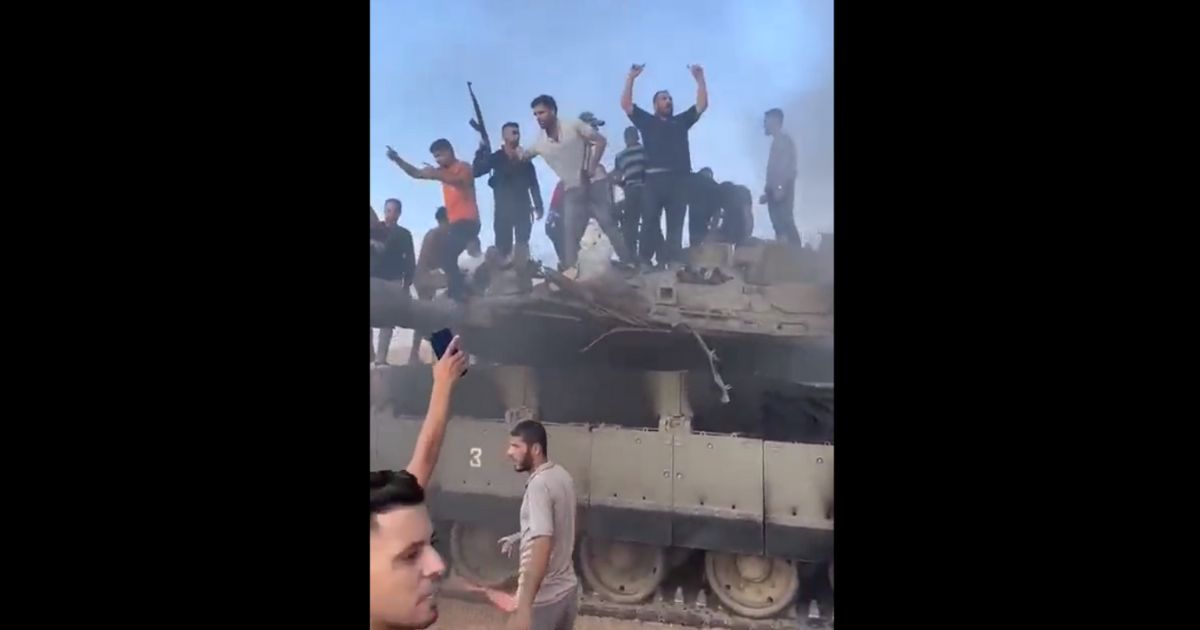 Hamas fighters are seen with a disabled Israeli tank its captured crew on the morning of Oct. 7, 2023.