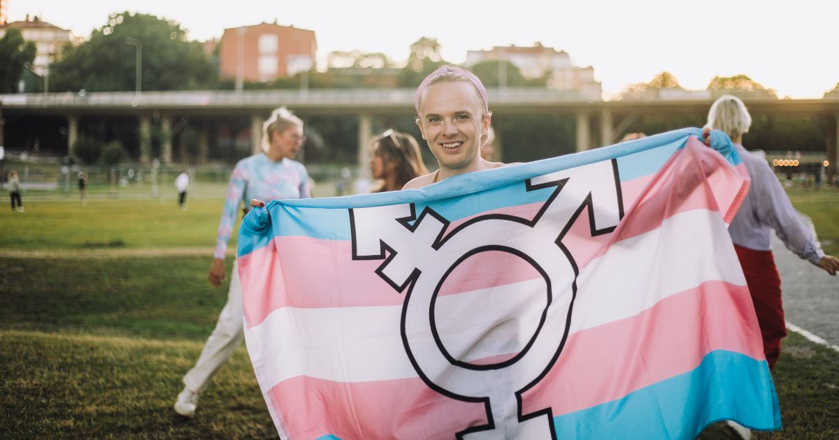 A girl holds up a flag with the transgender symbol in front of other children at a park. A federal court recently ruled that Iowa's Linn-Mar School District cannot force students and teachers to "respect" gender pronouns as it violates their First Amendment rights.
