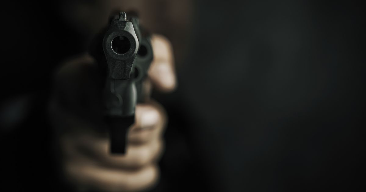 A stock photo shows a man holding a gun pointed at the camera.