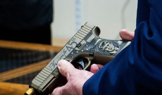 A closeup of former President Donald Trump's hands holding a Glock handgun his likeness on it.