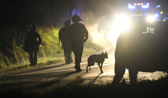 A member of law enforcement walks with a police dog outside a property on Meadow Road in Bowdoin, Maine, on Oct. 26.